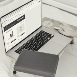 a laptop and a journal on a bed table